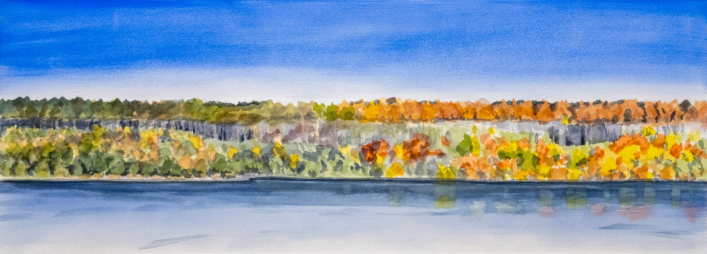Panoramic view of a cliff across the river with autumn foliage reflected in the water.